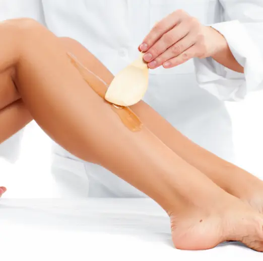 Beautician applying wax with a spatula on a woman's leg in our Málaga waxing salon