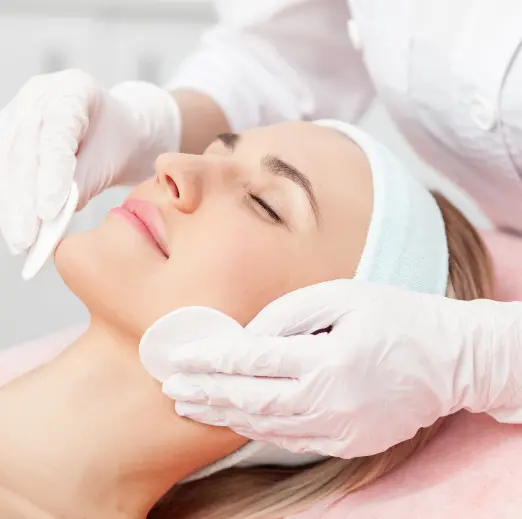 Beautician wearing gloves cleansing a client's face during a facial in Málaga