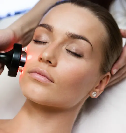 Facial device with red light applied to the temple of a relaxed woman