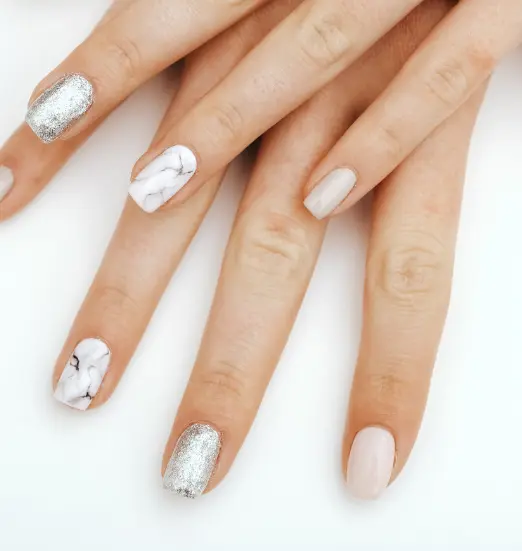 Uñas de gel nude con dos uñas efecto mármol y una plateada