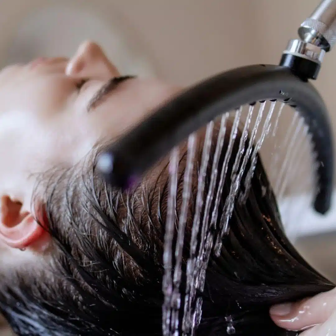 Client relaxing under a warm water cascade during our head spa ritual in Málaga